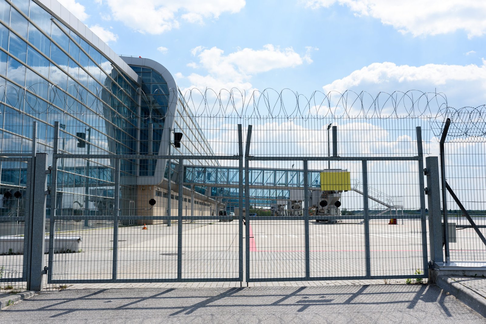 Portail grillagé surmonté de barbelés devant un site sécurisé
