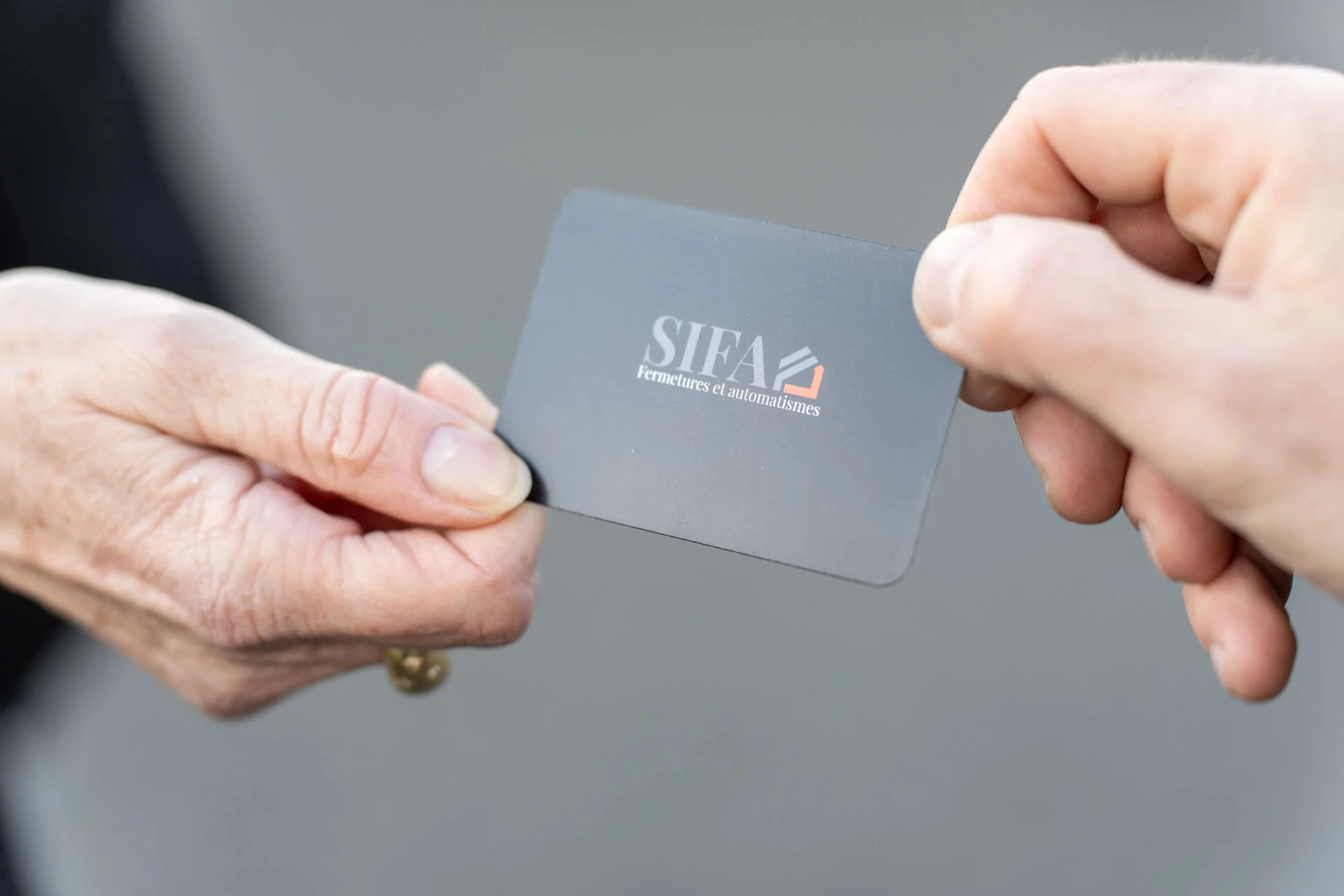 SIFA Automatismes : deux mains échangeant un badge SIFA