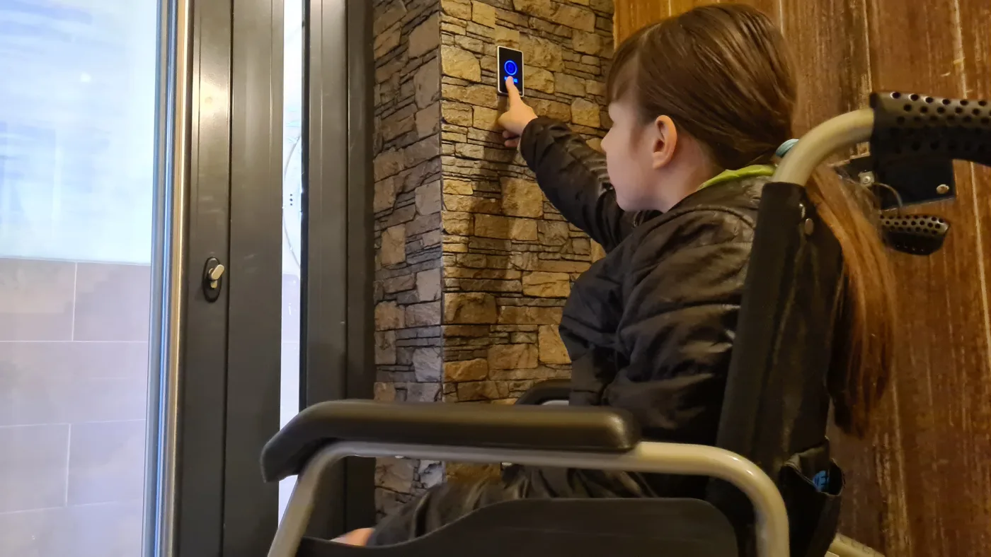 Personne en fauteuil roulant actionnant le bouton d’ouverture d’une porte