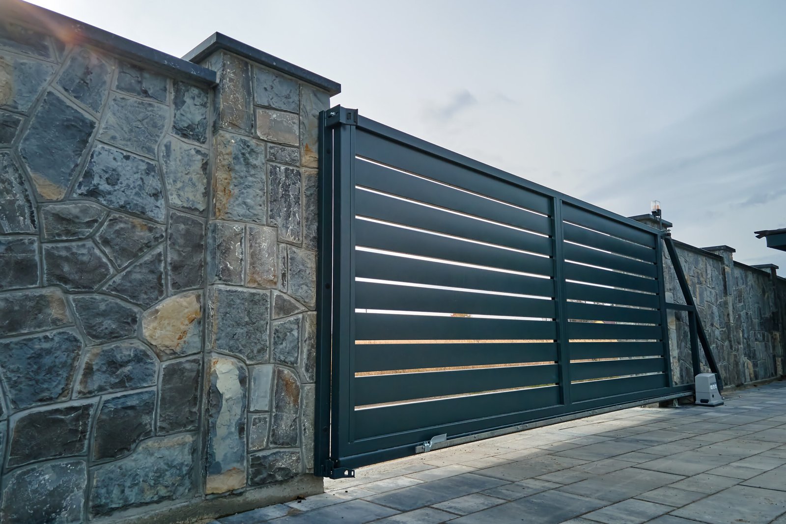 Portail coulissant anthracite entre des murs en pierre